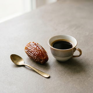 Single Medjool date beside a coffee cup showing size