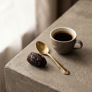 Premium Ajwa Dates beside a coffee cup showing size
